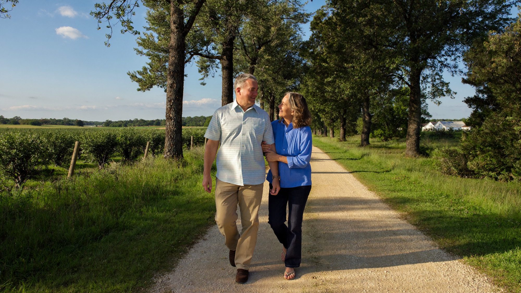 Retired Georgia couple walking down a sunny country lane while talking through their will and beneficiary designations